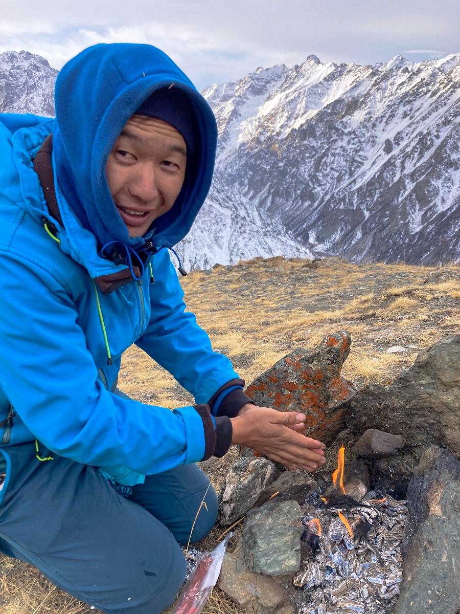 Mountain guide Jamil warming his hands from the camp fire